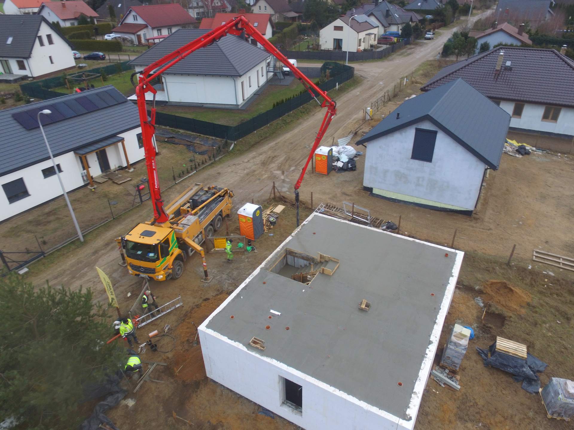 Kilka domów prefabrykowanych i pompa betonu z lotu ptaka — realizacja Tulio